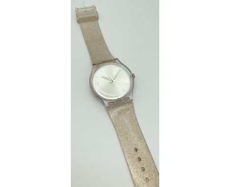 A unisex Swatch watch IS04 with brushed silver effect face and silver glitter silicone strap. Face approx. 3.5cm diameter. 