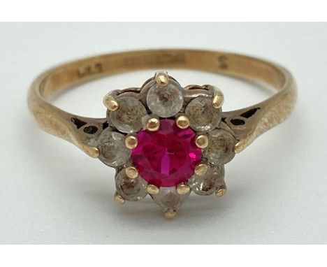 A 9ct gold flower cluster ring set with central pink ruby surrounded by 8 colourless spinel stones. Fully hallmarked inside b