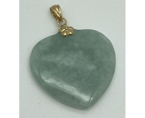 A heart shaped green jade pendant with 14k yellow gold flower shaped mount and bale. Bale stamped 14k and 585. Pendant approx