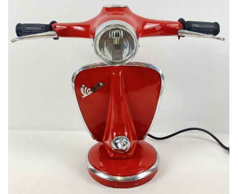 A novelty table lamp in the shape of the handlebars of a Vespa scooter, painted red. With moving brake levers and speedometer