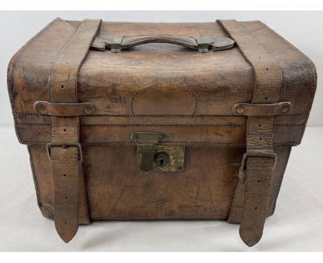 An antique leather travelling trunk with brass fixings, leather fastening straps and carry handle. Blue and white stripped co