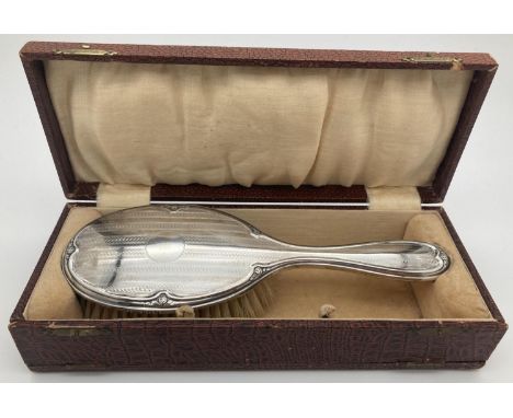 An Art Deco silver backed hair brush with engine turned decoration and central empty cartouche in original box. Hallmarked Bi