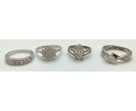 4 silver and clear stone set rings, in varying styles and sizes. A cubic zirconia cluster ring (size Q); a modern design ring