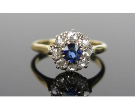 A Sapphire and Diamond Cluster Ring, central stone 5mm diameter, surround by eleven small diamonds, 11mm head, white metal cl