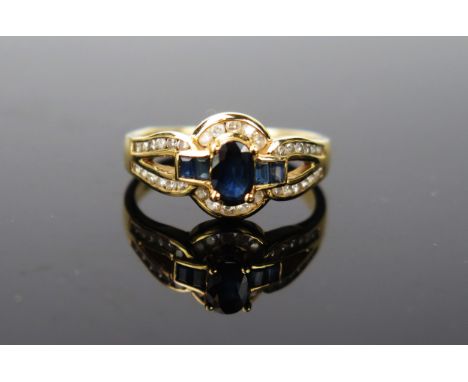 A modern Gold, Sapphire and Diamond ring, probably 18ct gold- marks poorly struck, the central oval flanked by four lighter b