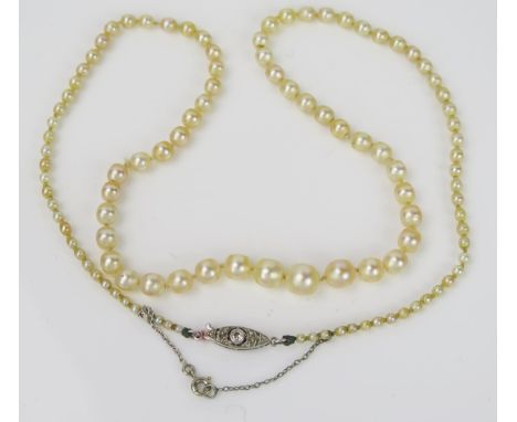 A Graduated Pearl Necklace, central pearl approximately 6.9mm, with an oval two stone diamond set in a millegrain white metal