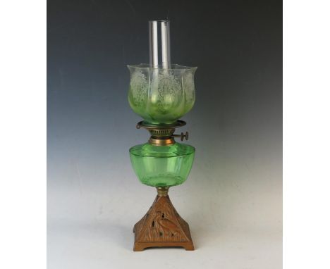A late Victorian cast iron and green glass oil lamp, with etched glass shade and chimney 54cm high. 