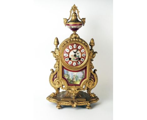 A late 19th century French gilt metal an porcelain mounted mantel clock of arched outline, with urn finial, scroll sides with