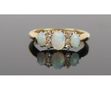 An Opal, Diamond and 18ct Gold Ring, the central oval opal flanked by six small diamonds, and two smaller opals, green, purpl