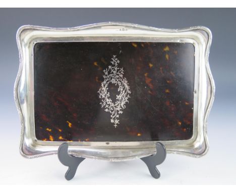 A George V tortoiseshell and silver dressing table tray, makers mark worn, London, 1919, with central inlaid cartouche, enclo