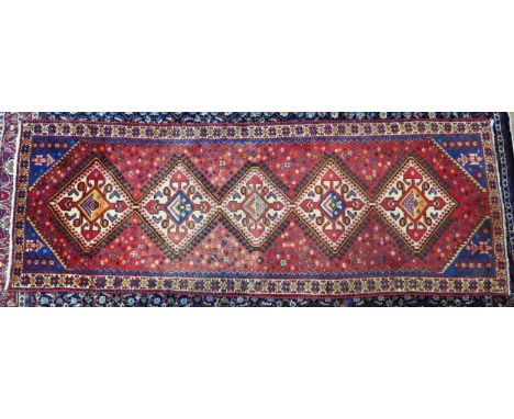 A Hamadan runner, with a five hooked lozenge pole medallion to a wine red field, with powder blue floral spandrels enclosed b