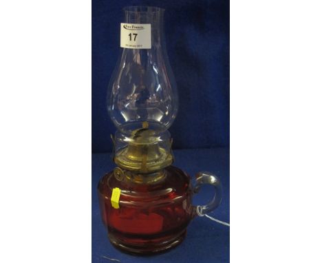 Brass single burner chamber oil lamp with cranberry glass reservoir, loop handle and clear chimney.