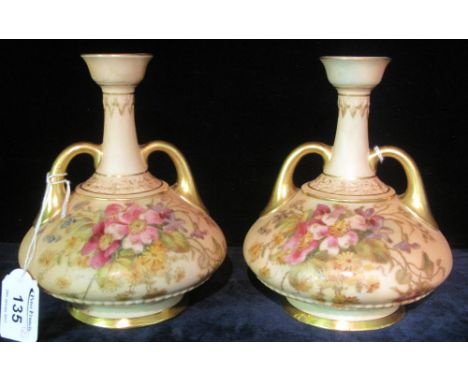 Pair of Royal Worcester porcelain peach ground, baluster shaped, two-handled vases, overall gilded and painted with sprays of