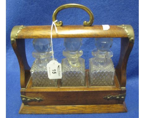 Small oak three bottle tantalus, having three small, cut glass, square section decanters with facet stoppers.