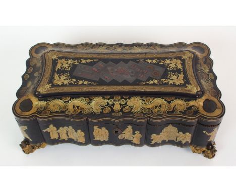 A Chinese export black and gold lacquered games box gilt with processions of figures, dragons and playing cards enclosing two