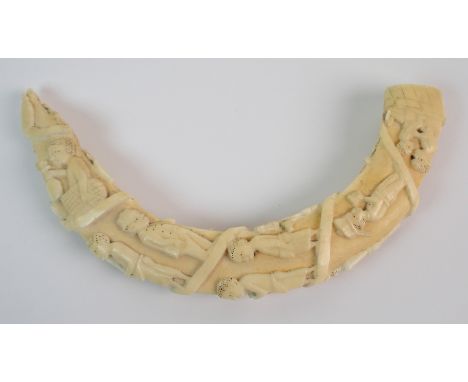 A Congo ivory tusk carved with a procession of native and European figures, 21cm long