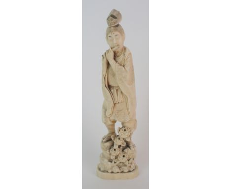 A Japanese okimono of a musician standing and playing a flute on a rock issuing flowers (part of flute lacking), signed, 28cm