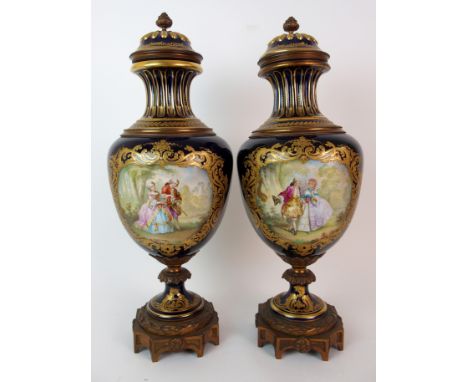 A pair of Sevres-style painted porcelain gilt metal mounted lidded urns each with cobalt blue ground, tapering fluted neck, r
