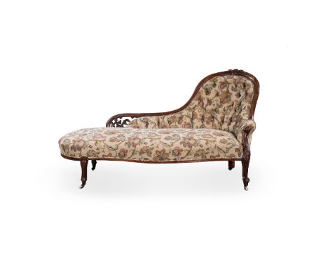 A VICTORIAN MAHOGANY AND UPHOLSTERED CHAISE LONGUE the pierced shaped and curved back surmounted by a leaf cresting above a b