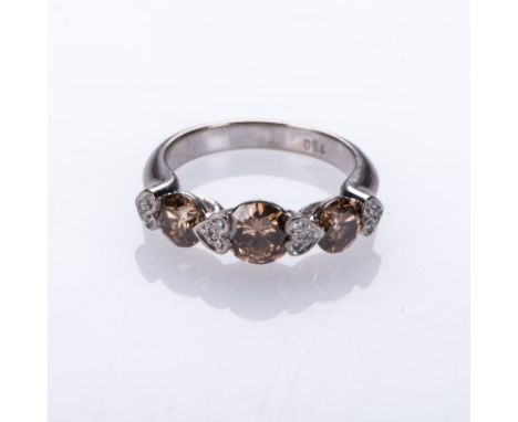 A DIAMOND TRILOGY RING centred by a round brilliant-cut diamond, weighing approximately 0.64cts, channel-set between two hear