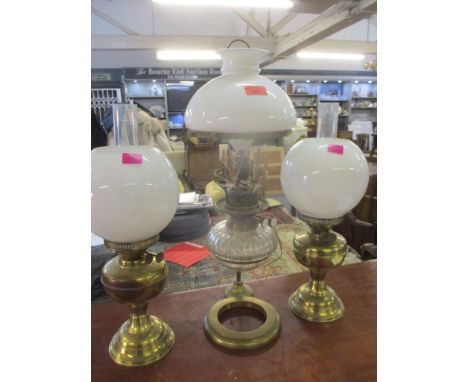 An early 20th century oil lamp converted to electricity having a brass frame together with a pair of brass oil lamps, all wit