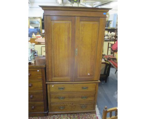Edwardian light oak wardrobe chest, the top with stepped cornice and twin panelled doors over a base of three long drawers wi