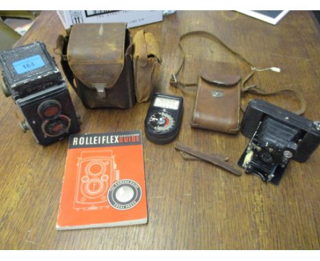 A Roliflex camera with a leather case, a guide book and Western Master light meter, along with a folding pocket cameraLocatio