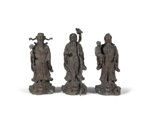 A SET OF THREE CHINESE BRONZE FIGURES OF IMMORTALS,each modelled standing on the back of a dragon, dressed in Ming costume an