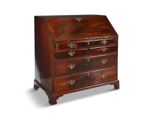 A GEORGE III MAHOGANY SLOPE-FRONT BUREAU,the figural fall front panel with brass escutcheon , enclosing a fitted interior wit