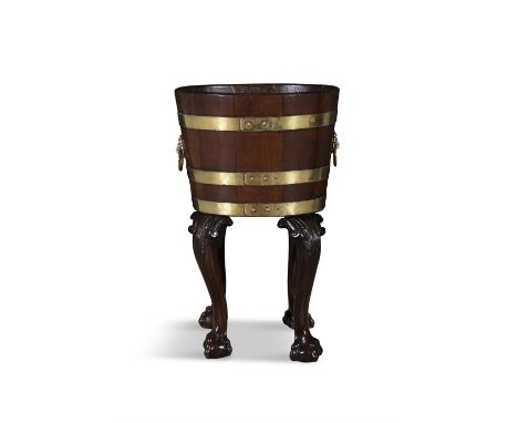 AN IRISH GEORGE III MAHOGANY AND BRASS BOUND OVAL BUCKET ON STAND,fitted with lion mask ring handles, on acanthus carved cabr