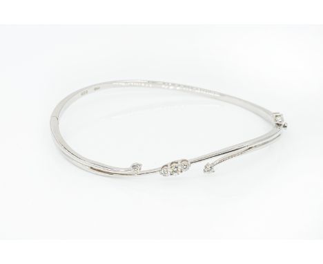 A DIAMOND OVAL HINGED BANGLEThe front mounted with five round brilliant cut diamonds, in 18ct white gold, on a snap clasp, gr