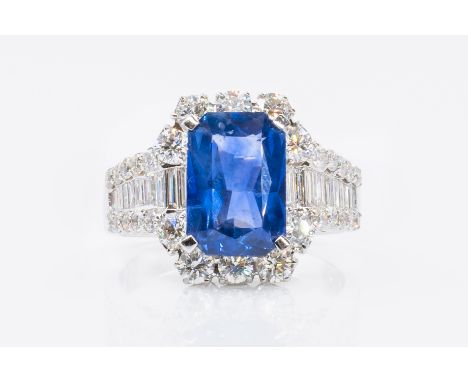 A SAPPHIRE AND DIAMOND DRESS RINGFeaturing a central step-cut blue sapphire (weight 3.55 carats) surrounded by baguette and r