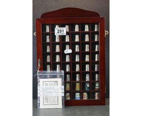 A collection of thimbles contained within a display cabinet to include hallmarked silver and ceramic examples. 