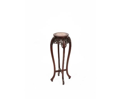 A Chinese hardwood urn stand the circular marble inset top with a beaded edge above a pierced floral carved apron, on scroll 