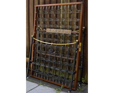 A late 19th Century black painted and brass mounted bed frame, the foot board cast with a central floral design, on ceramic c