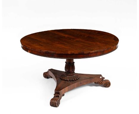 A William IV rosewood centre table, the circular top on turned column issuing from a lappet carved sconce to a triform base w