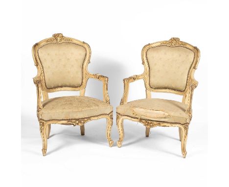 A pair of Louis XV style cream painted and parcel gilt open armchairs the cartouche backs with gilt crests, on upholstered se