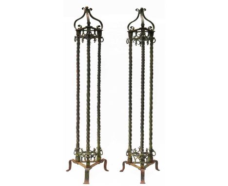 A large pair of 19th Century wrought iron lamp stands, with scrolling tops on three spiral columns and a tripod base, hung wi