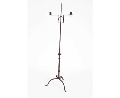 A 17th Century standard iron candelabra, with two candle sconces, on a square pole with knopped embellishment and a scrollwor