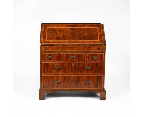 An early 18th Century walnut and featherbanded bureau, the sloping fall enclosing an interior of pigeon holes, a covered well