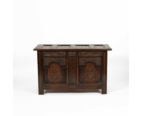 A 17th Century oak coffer, the quadruple panel cover above a twin panel front with carved and inlaid decoration, on stiles, 1