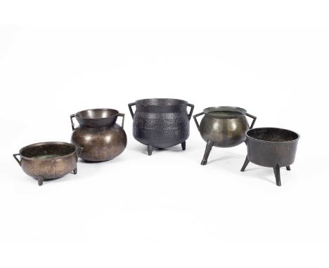 A 17th Century iron cauldron with two angled handles to a bulbous body, cast with two rings and on tripod feet, 33cm wide, 24