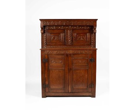 A Charles II oak press cupboard, West Country, the upper part enclosed by carved panel doors and with overhanging canopy with