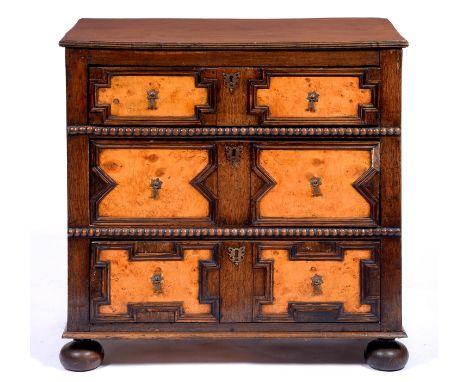 An oak and burr walnut geometric moulded chest of drawers, 19th/early 20th c,&nbsp; in William III style, with brass axe head