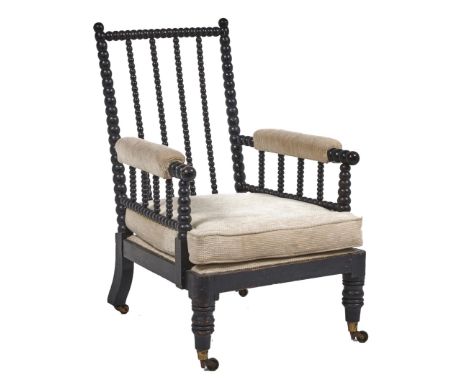 A George IV bobbin turned and ebonised open armchair, with padded arms, brass castors, seat height 30cm, with two cushions Co
