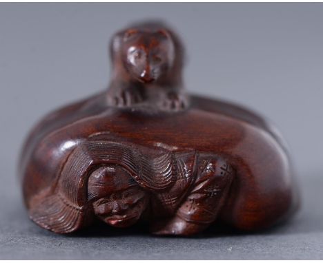 A Japanese boxwood netsuke&nbsp;of a hunter with a matchlock gun (Hinawaju) caught beneath a badger (tanuki), Edo / Meiji per