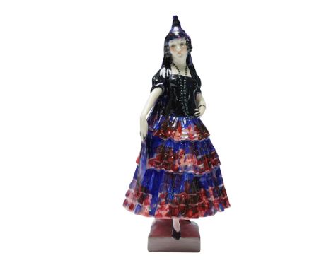 The figure is dressed in a multi-tiered ruffled skirt with red and blue coloration and a black bodice. She is adorned with a 