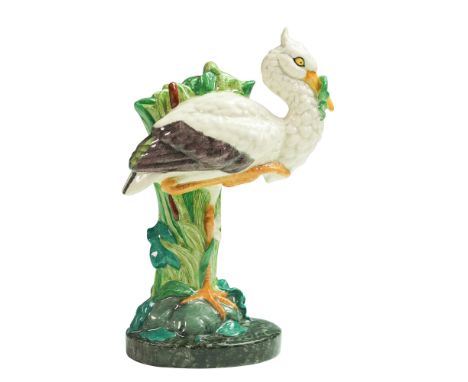 This figure depicts a stork standing among tall cattails with a serpent in its beak. The design draws inspiration from an ear