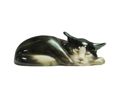 Rare. This glazed ceramic figure depicts a black and white cat curled up in a resting position with its head on its front paw