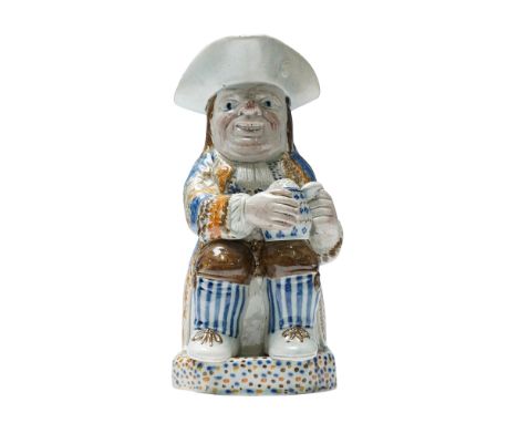 Early English pearlware Toby jug, hand-painted in a palette of blue, orange, brown, and cream. The jug is modeled as a seated